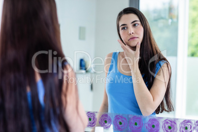 Unsmiling brunette looking her reflection in the mirror