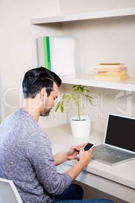 Thoughtful man using smartphone and laptop