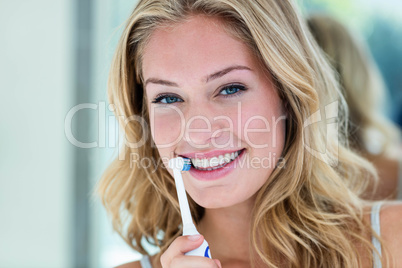 Happy blonde brushing her teeth in the bathroom