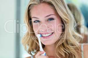 Happy blonde brushing her teeth in the bathroom