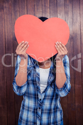 Woman hiding her face behind paper heart