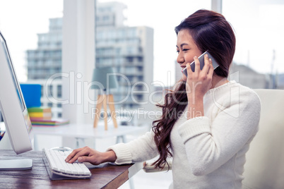 Smiling Asian woman on phone call using computer