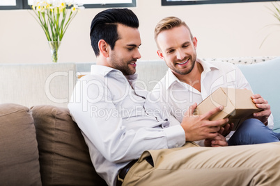 Smiling man offering gift to his boyfriend