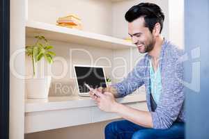 Happy man using smartphone and laptop