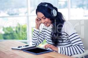 Smiling Asian woman with headphones using tablet