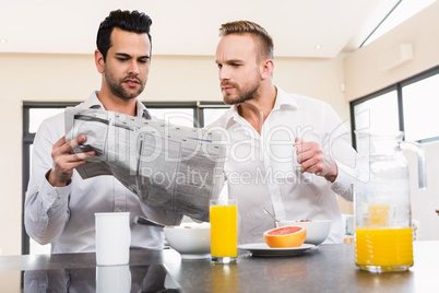 Concentrated gay couple reading newspaper