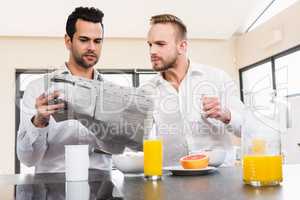 Concentrated gay couple reading newspaper