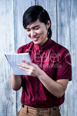 Smiling hipster takes notes with his smartphone