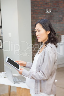 Serious pregnant woman using tablet