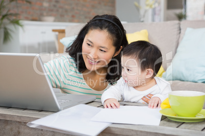 Happy mother with baby daughter using laptop