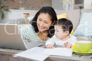 Happy mother with baby daughter using laptop