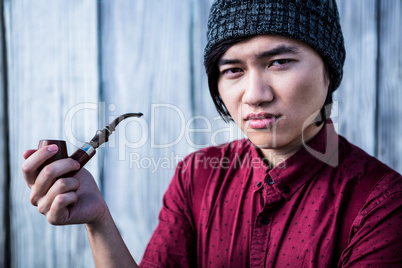 Thoughtful hipster smoking pipe