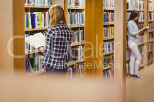 Serious students reading next to bookshelf
