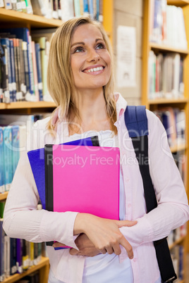 Female student holding textbooks in the library