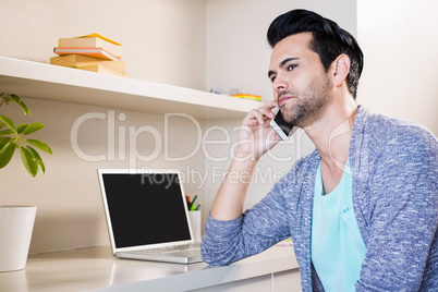 Thoughtful man using smartphone and laptop