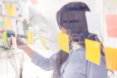 Asian businesswoman using sticky notes on wall