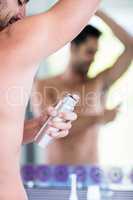 Handsome shirtless man putting deodorant