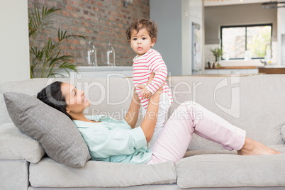 Smiling brunette playing with her baby