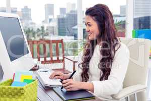 Smiling Asian woman using digital board and computer