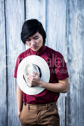 Thoughtful hipster holding a straw hat