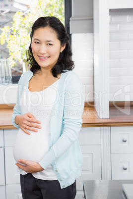 Portrait of smiling pregnant woman touching her belly