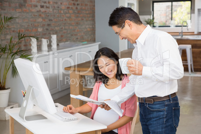 Smiling man showing newspaper to his pregnant wife