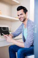 Happy man using smartphone and laptop