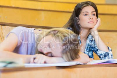 Bored student listening while classmate sleeping