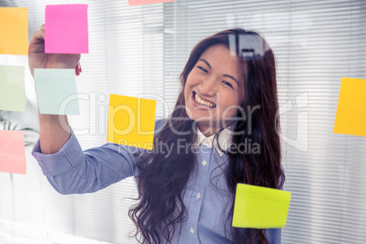 Asian businesswoman using sticky notes on wall