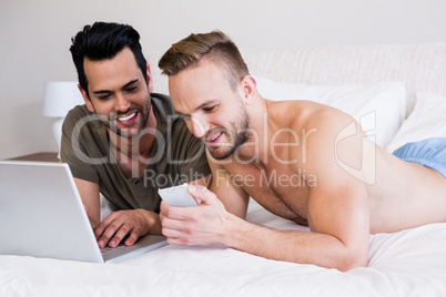 Gay couple using smartphone and laptop