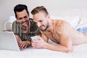 Gay couple using smartphone and laptop