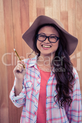 Smiling Asian woman with hat holding pencil