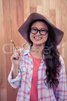 Smiling Asian woman with hat holding pencil