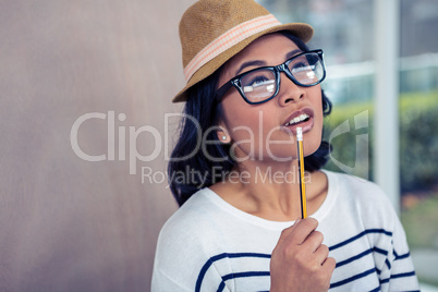 Thoughtful Asian woman with pencil on mouth
