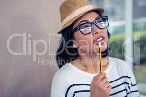 Thoughtful Asian woman with pencil on mouth