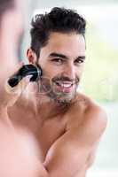 Handsome man shaving in the mirror