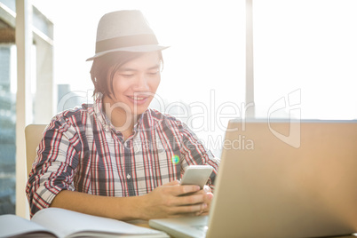 Smiling hipster businessman using smartphone