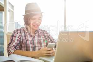 Smiling hipster businessman using smartphone