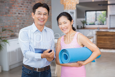 Happy couple using tablet and holding mat