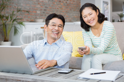 Smiling couple using laptop and smartphone