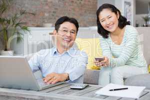 Smiling couple using laptop and smartphone