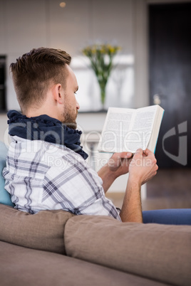 Handsome man reading a book on the couch