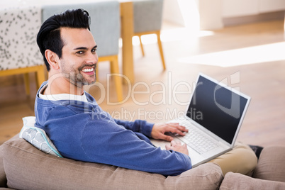 Handsome man using laptop on couch