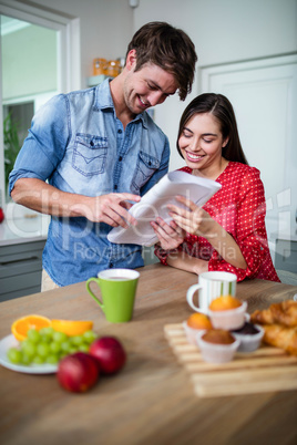 Happy couple having breakfast and reading newspaper