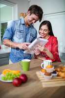 Happy couple having breakfast and reading newspaper