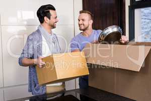 Smiling gay couple unpacking cardboard