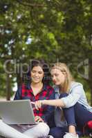 Smiling students using laptop