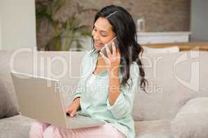 Smiling brunette on a phone call using laptop