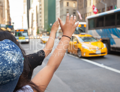 Tourists call a yellow cab in Manhattan with typical gesture
