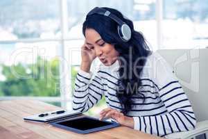 Smiling Asian woman with headphones using tablet